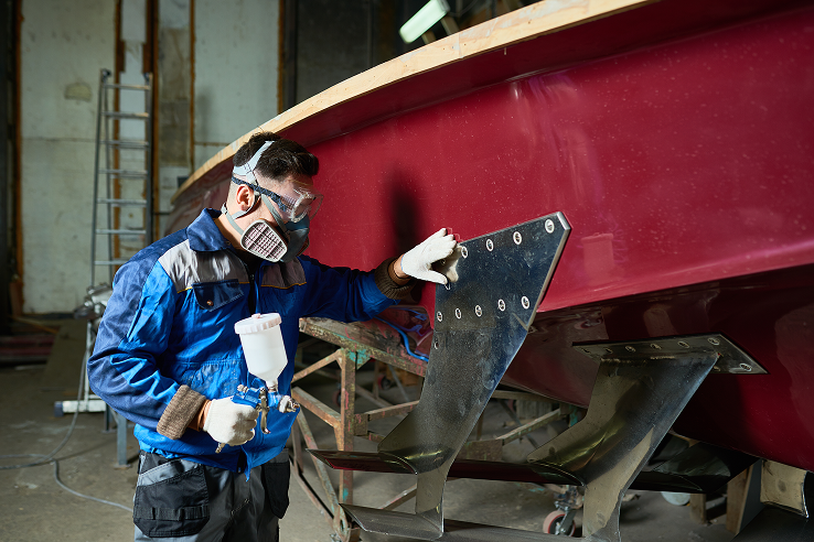 man painting boats in yacht workshop
